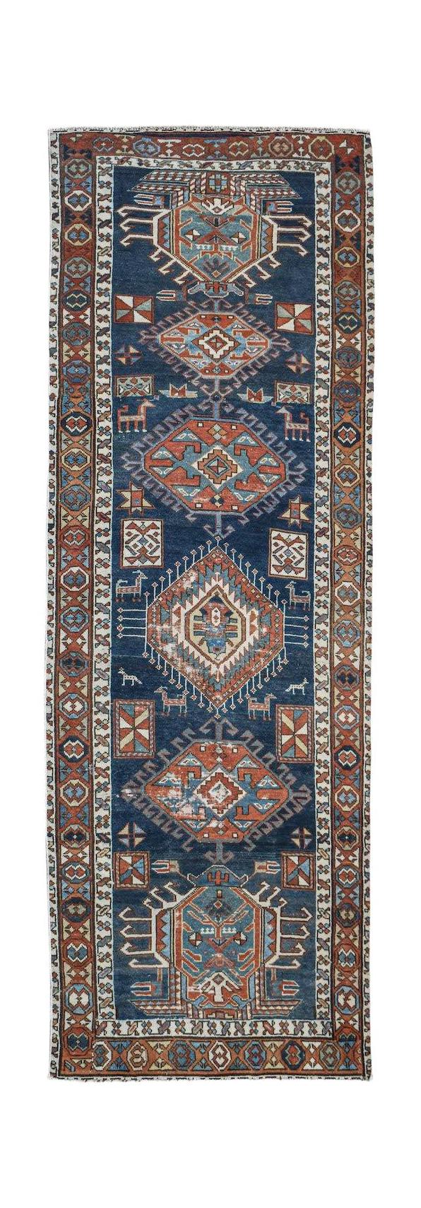 A vintage handwoven Caucasian Shirvan runner featuring geometric medallions on a blue field.