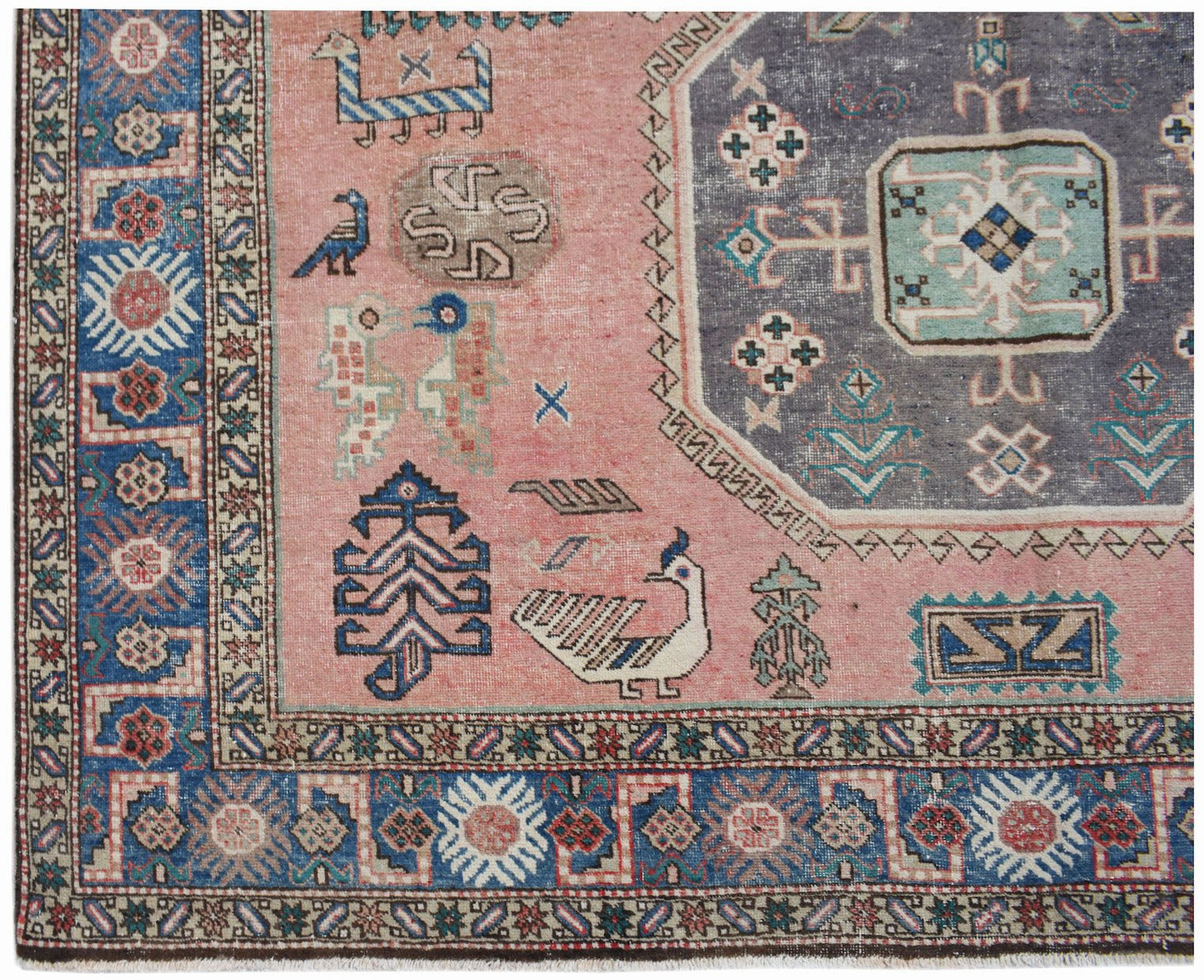 A vintage handmade Caucasian wool rug featuring a pink field with traditional bird and floral motifs.
