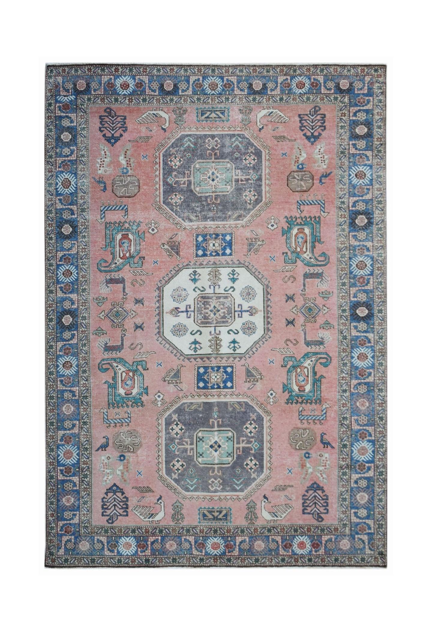 A vintage handmade Caucasian wool rug featuring a traditional geometric pattern on a pink field.