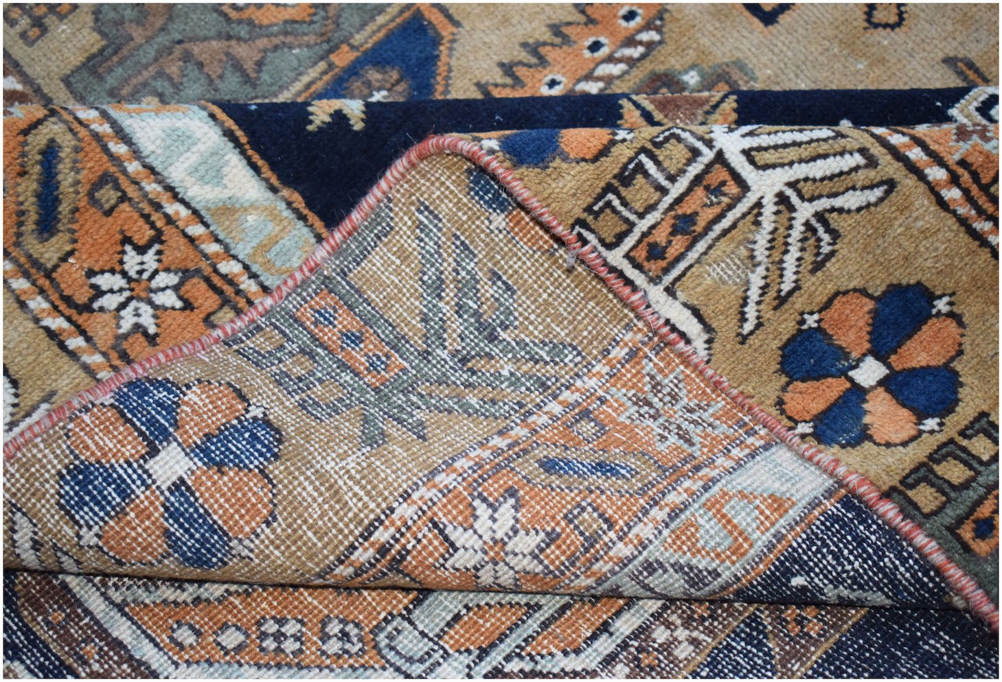 A handwoven vintage Persian rug featuring geometric floral patterns in blue, orange, and tan.