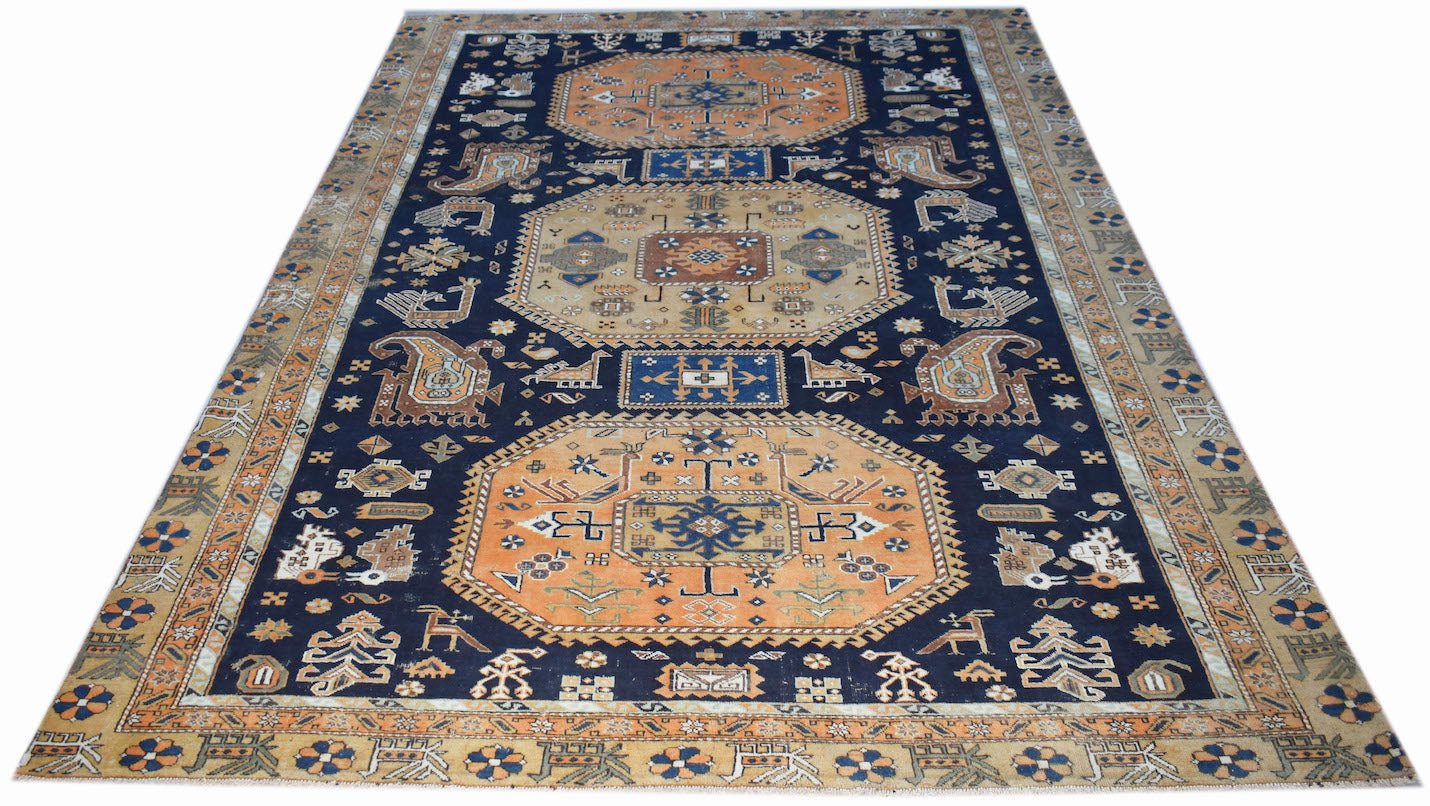 A handwoven vintage Caucasian rug featuring geometric medallions on a dark blue field.