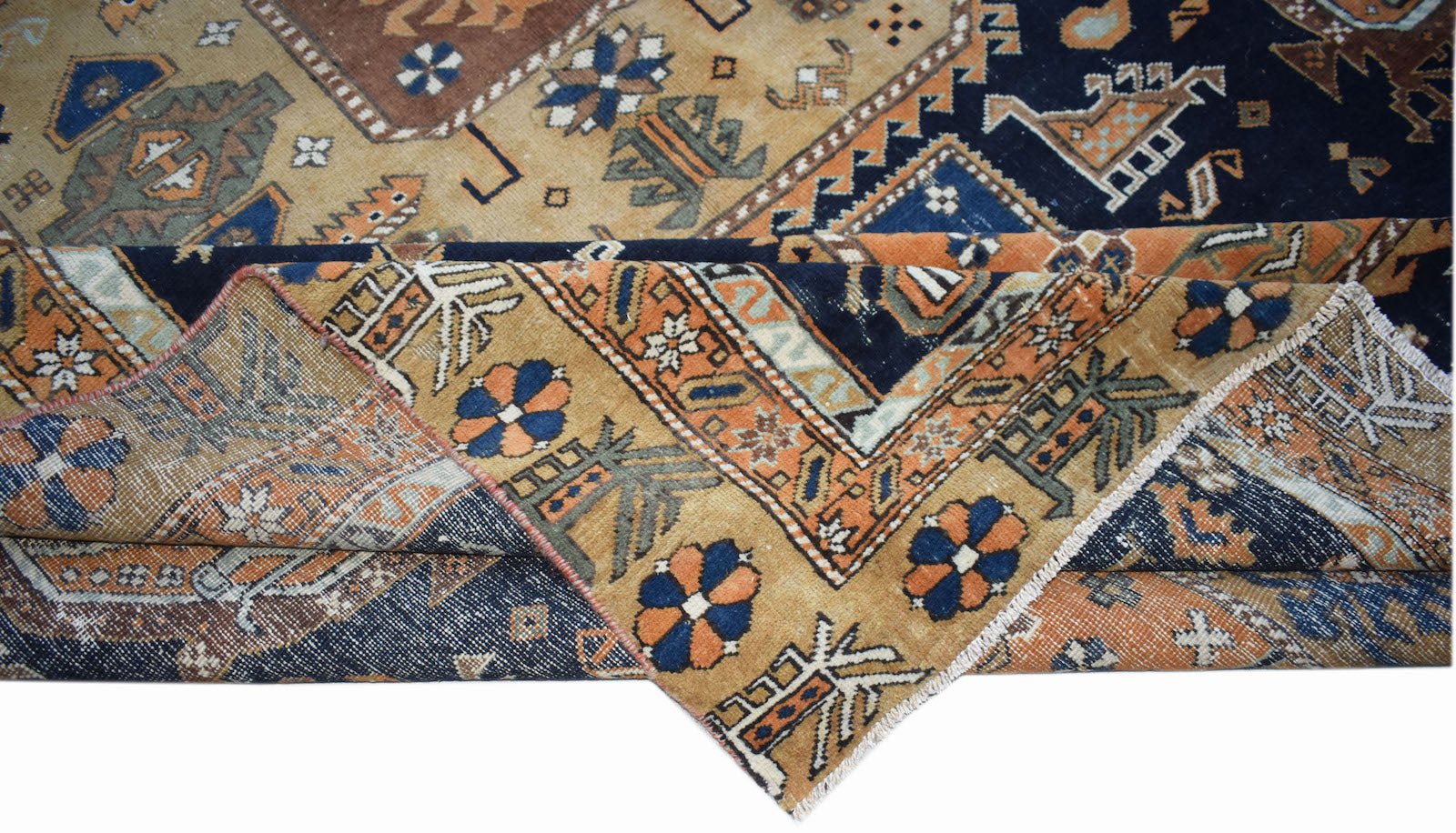 A handwoven vintage Caucasian rug featuring geometric patterns in blue, orange, and tan wool.