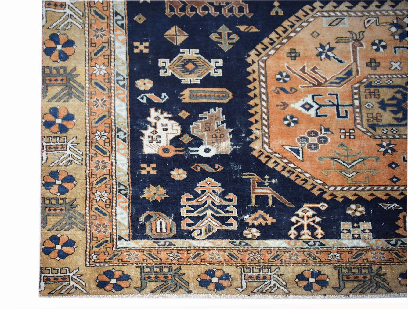 A vintage handwoven Caucasian rug featuring a dark blue field with geometric motifs and orange borders.