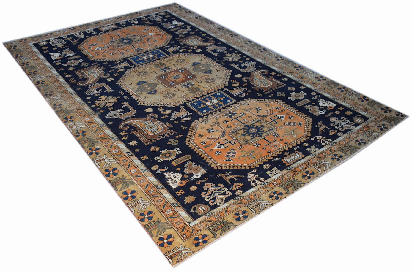A handwoven vintage Caucasian rug featuring geometric medallions on a dark blue field.
