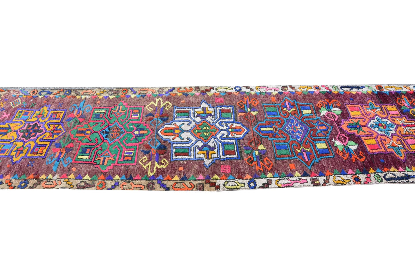 A vintage Kurdish Herki runner featuring vibrant geometric tribal motifs on a dark wool base.