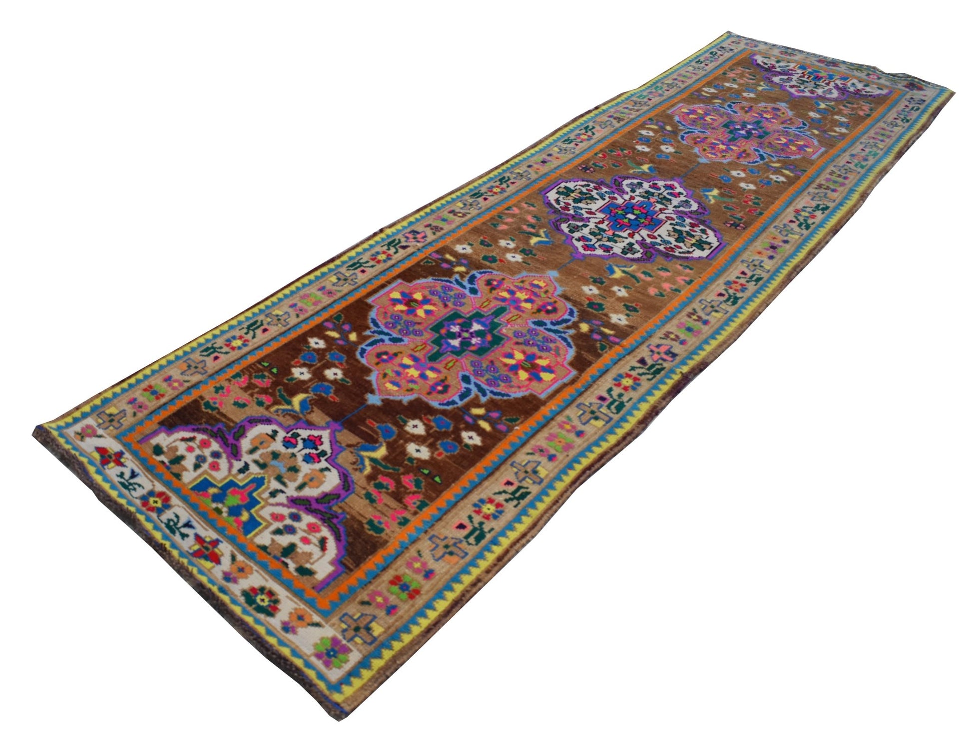 A vintage handmade Kurdish Herki runner featuring colorful tribal motifs on a brown wool background.