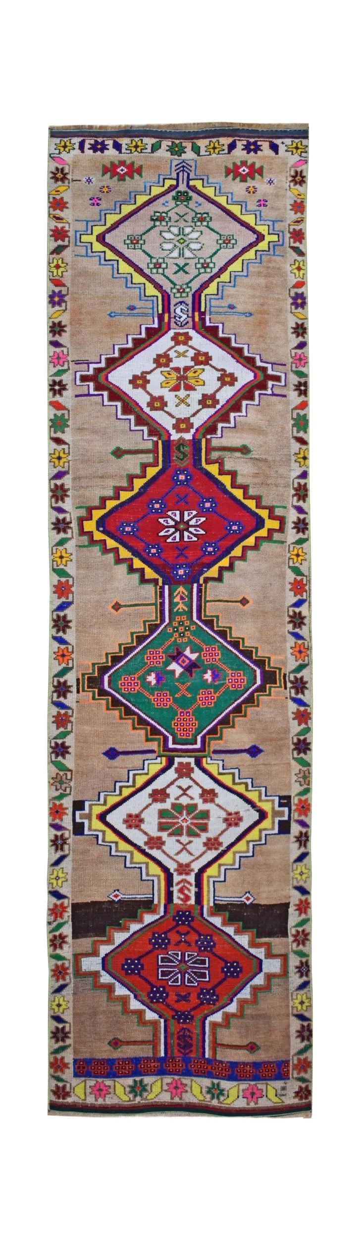 A vintage Kurdish Herki runner featuring tribal geometric motifs in vibrant colors on a tan base.