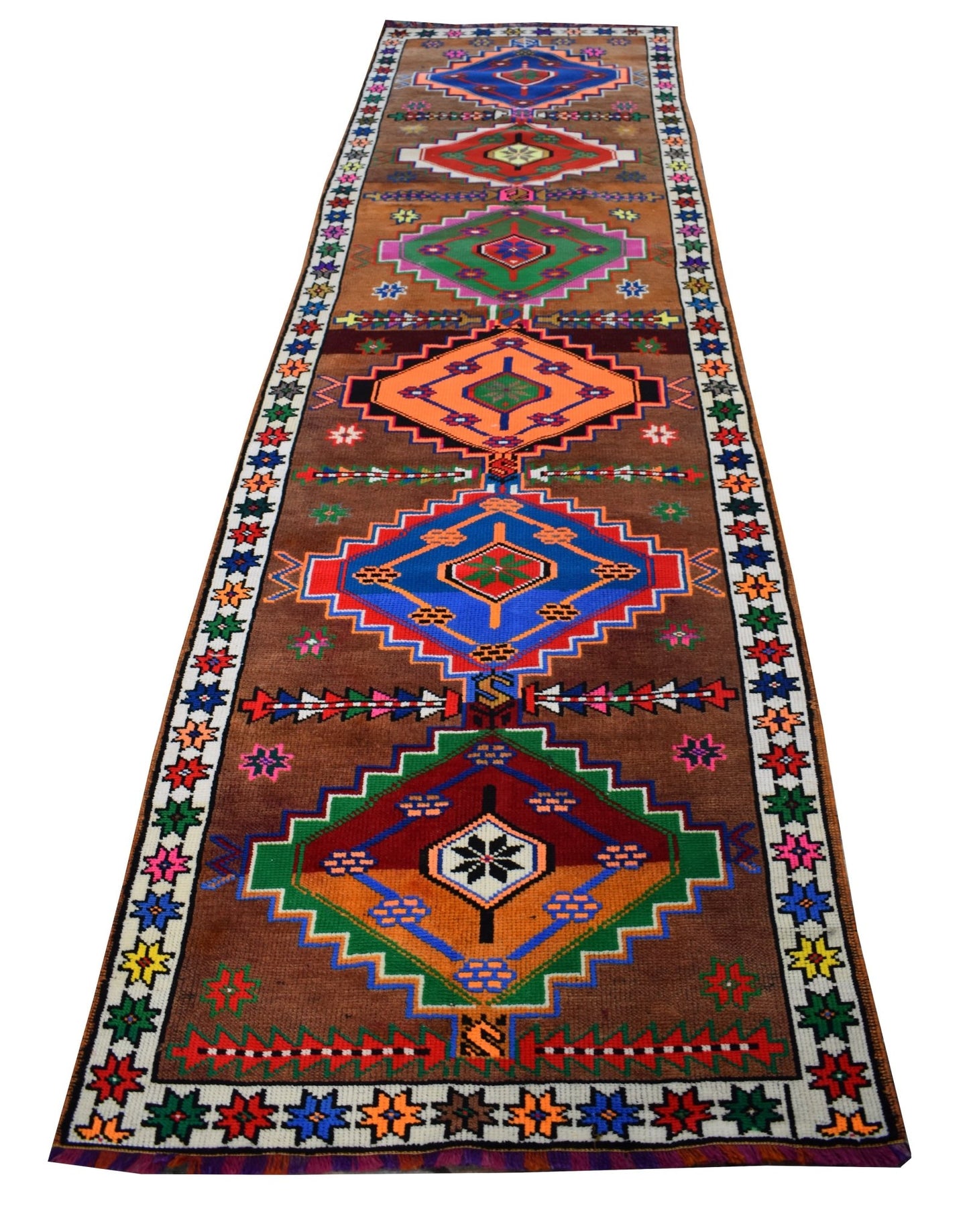 A vintage handmade Kurdish Herki runner featuring colorful geometric tribal motifs on a brown field.