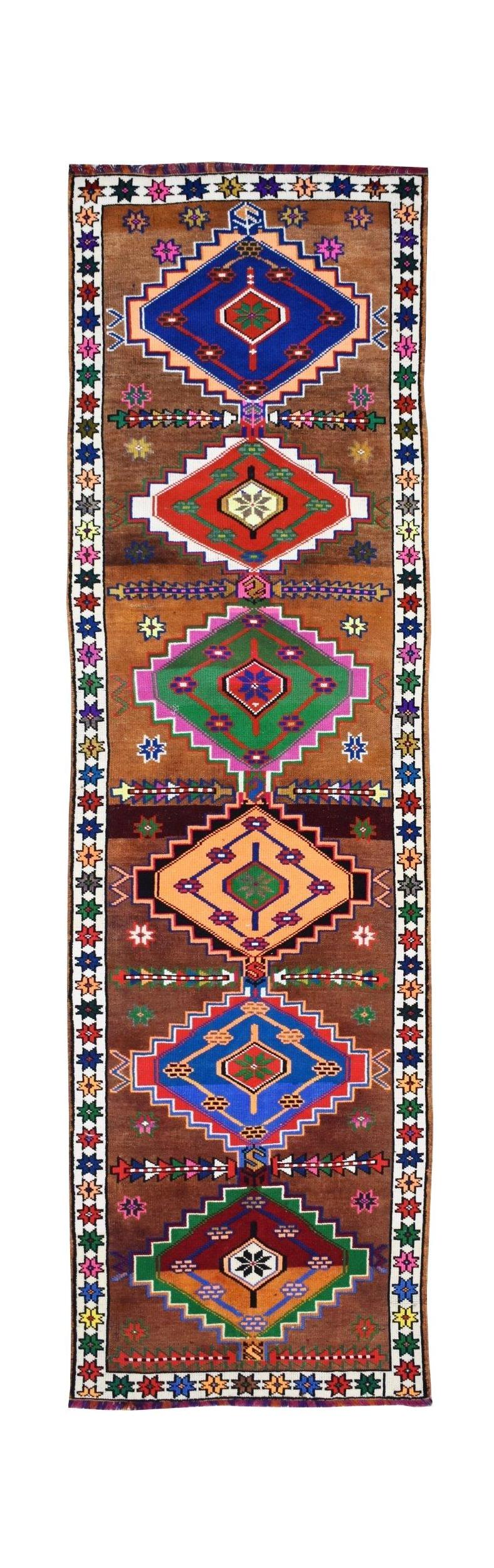 A vintage Kurdish Herki runner featuring colorful geometric tribal motifs on a brown wool field.