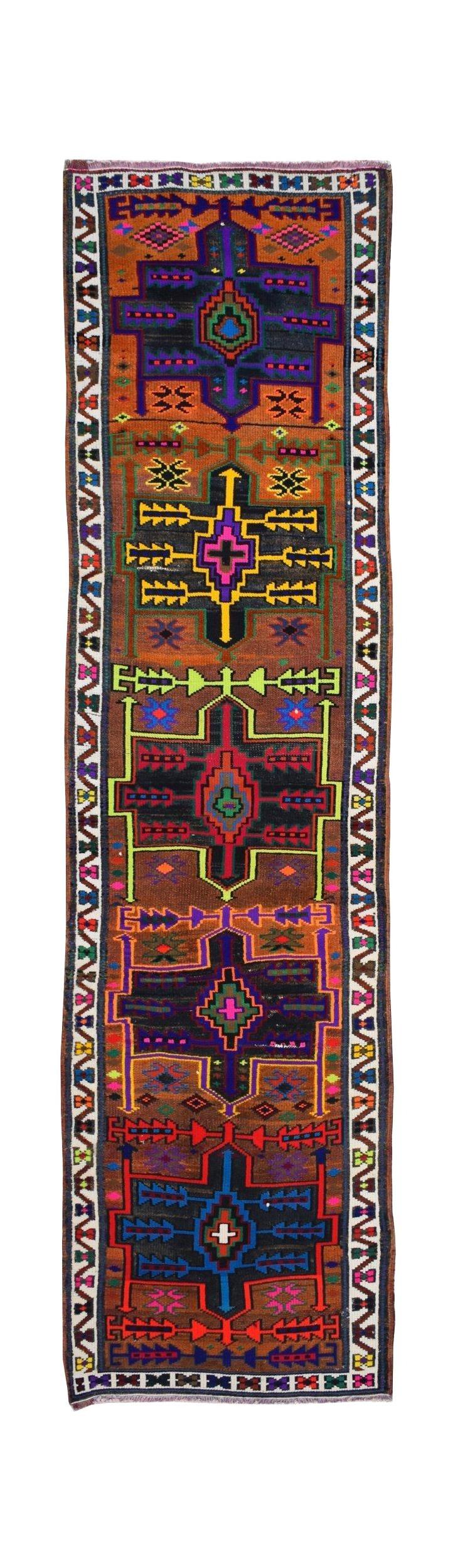 A vintage handmade Kurdish Herki runner featuring colorful tribal motifs on a brown wool background.
