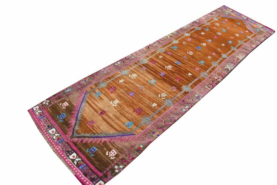 A vintage Kurdish Herki runner featuring tribal motifs in vibrant neon colors on a brown wool base.