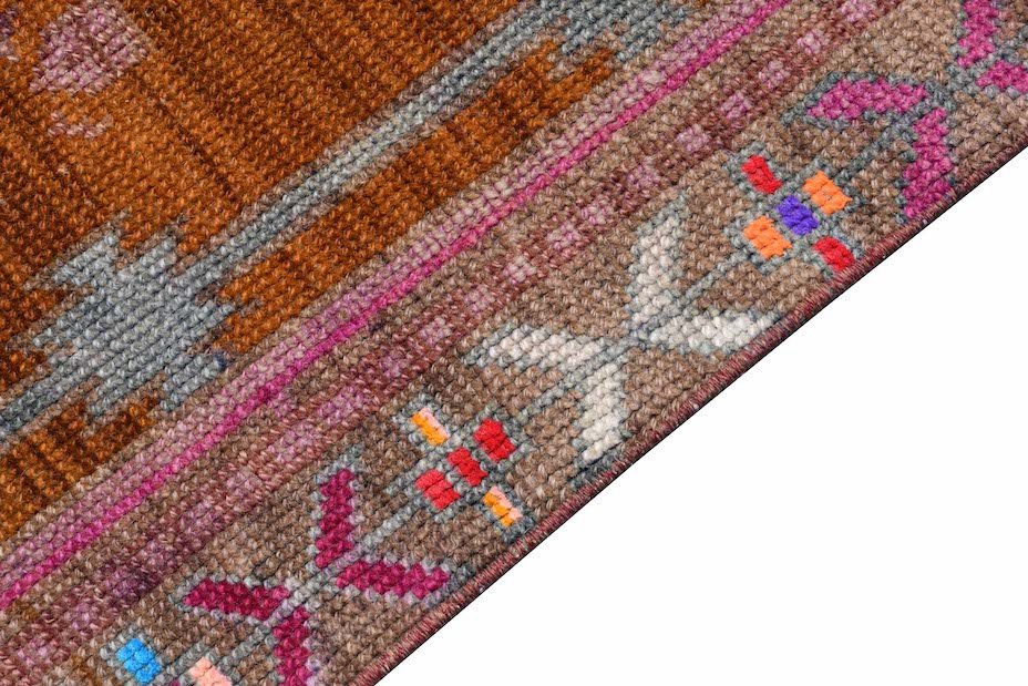Vintage Kurdish Herki runner with tribal patterns in brown, pink, and gray.