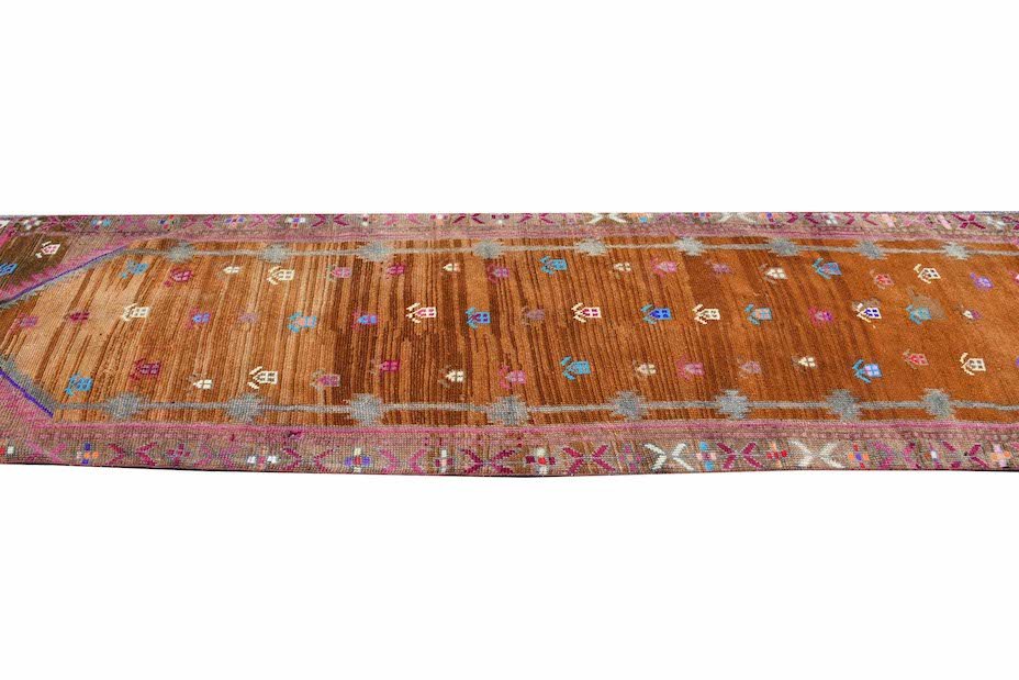 Vintage Kurdish Herki runner with tribal motifs in brown and pink.