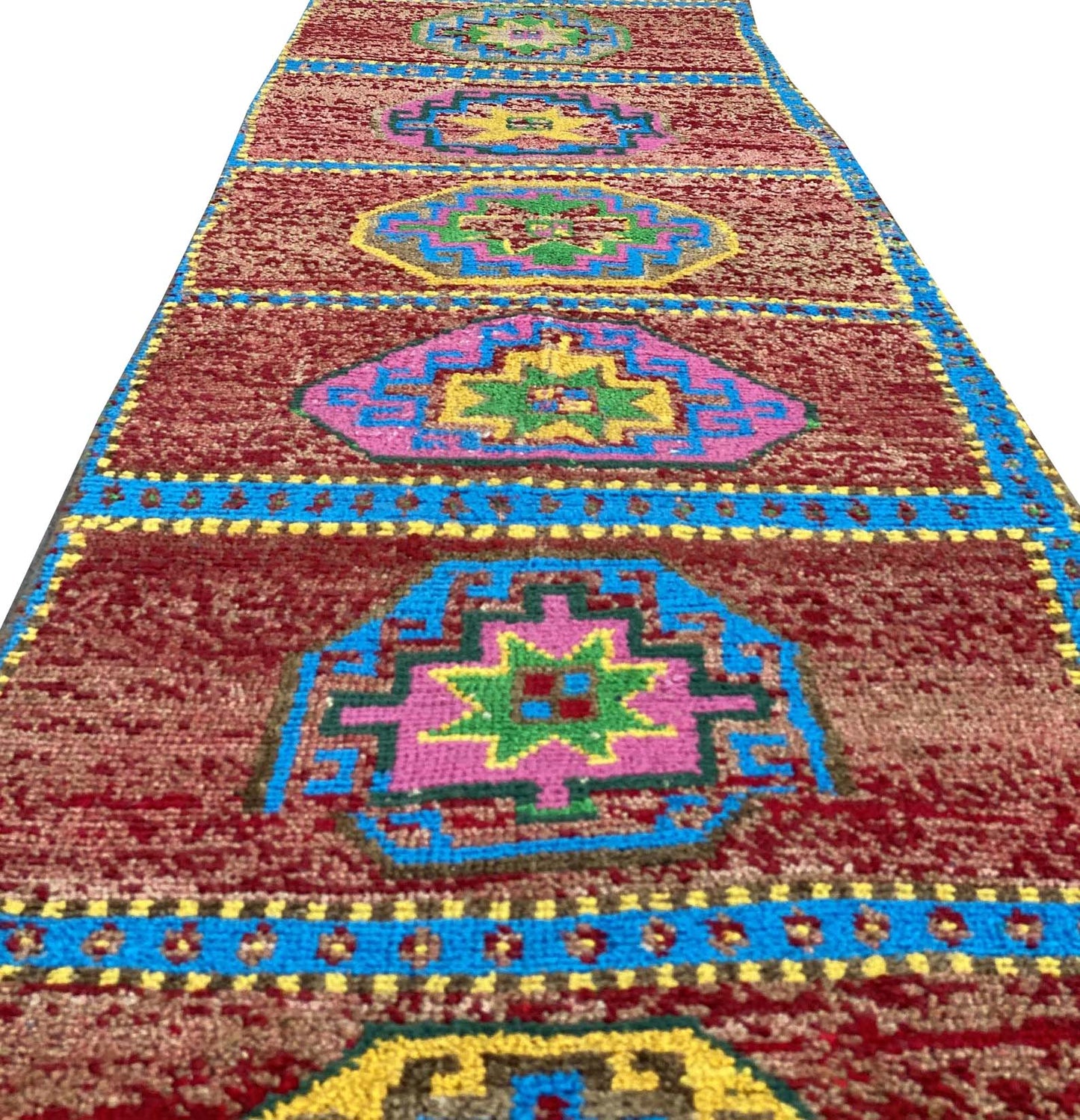 A vintage Kurdish Herki runner featuring geometric medallions in vibrant colors on a red field.