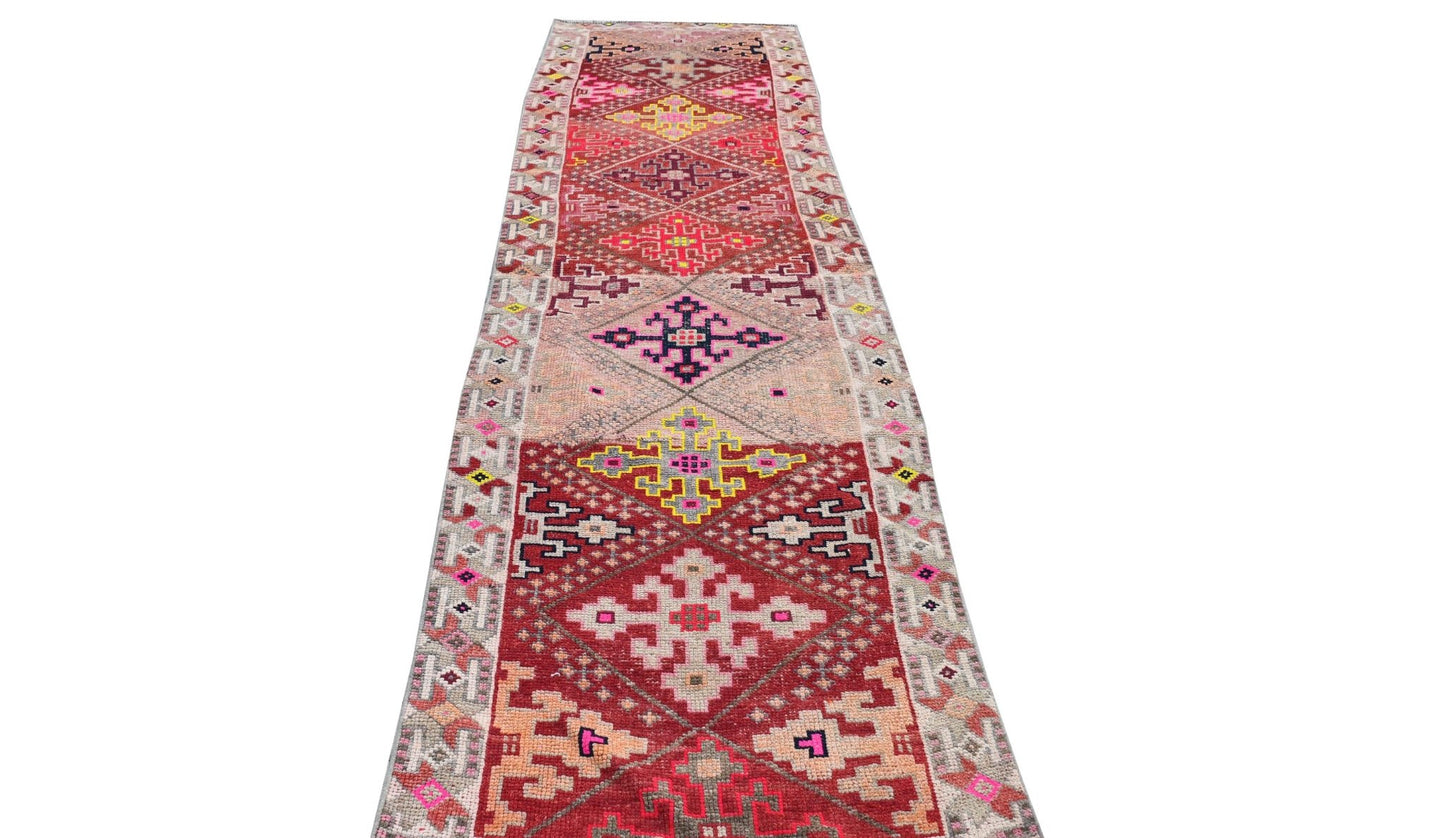 Vintage Kurdish Herki runner with tribal motifs in red, pink, and yellow.