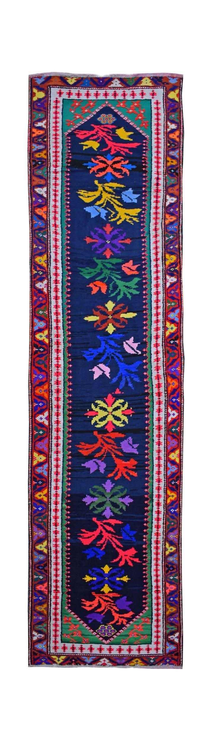 A vintage Kurdish Herki runner featuring vibrant tribal motifs on a deep blue wool background.