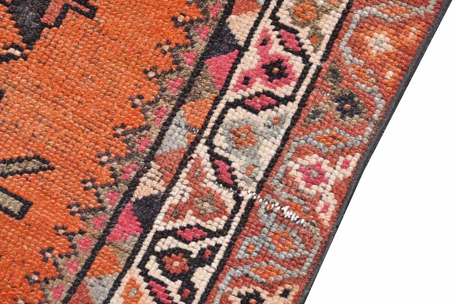 A vintage Kurdish Herki runner featuring tribal motifs in vibrant orange, pink, and grey tones.