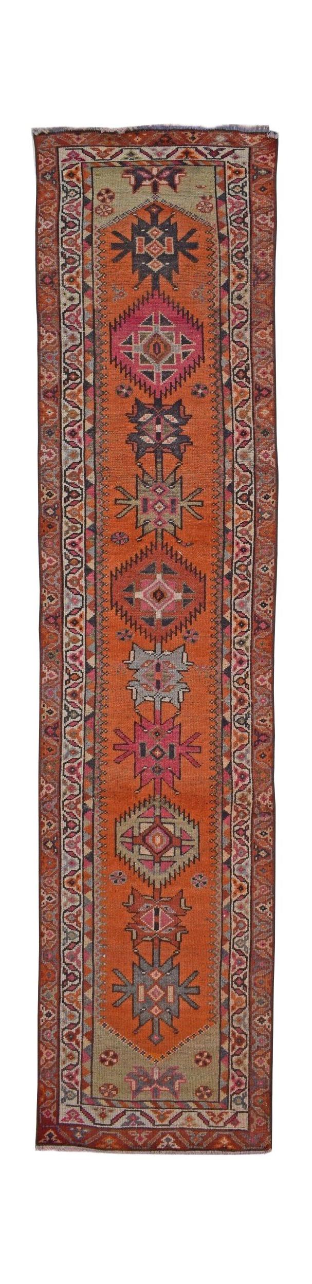 A vintage Kurdish Herki runner featuring tribal geometric motifs in vibrant orange and pink tones.