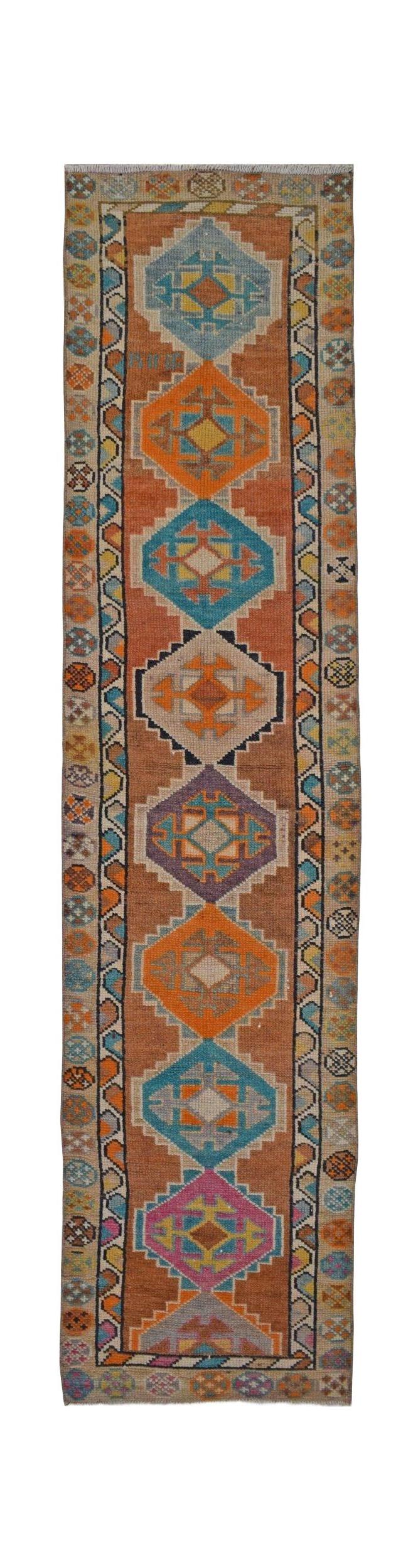 Vintage Kurdish Herki runner with geometric tribal patterns in orange, blue, and purple.