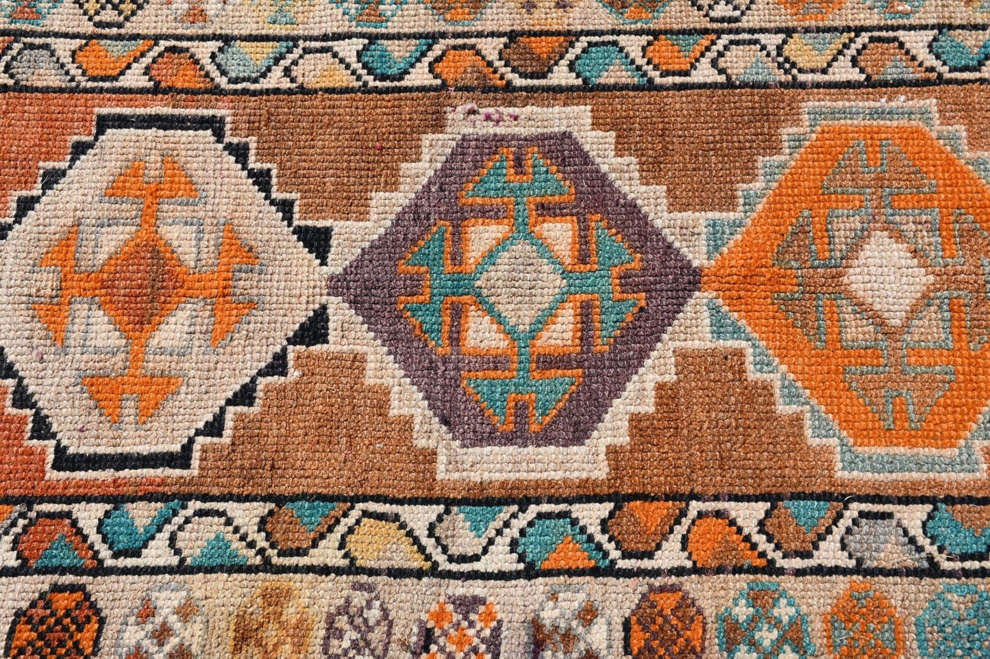 A vintage Kurdish Herki runner featuring geometric tribal motifs in vibrant orange and teal.