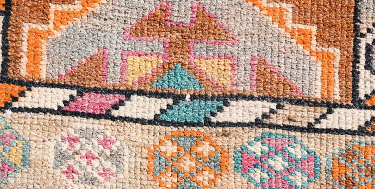 Close-up of a vintage Kurdish Herki runner with geometric patterns in orange, pink, and teal.