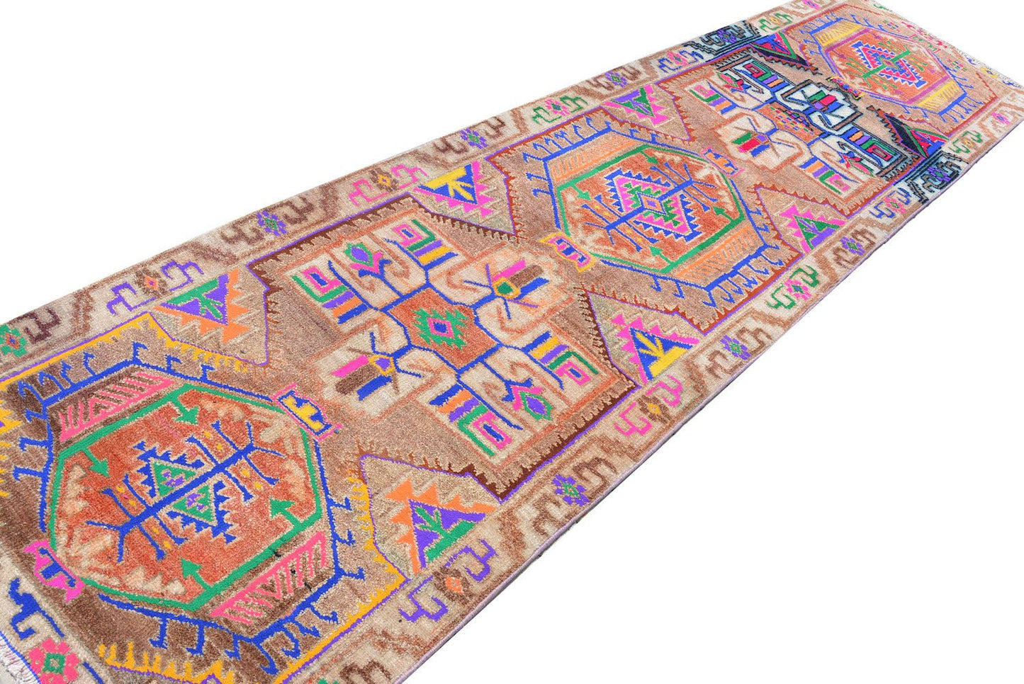 A vintage Kurdish Herki runner featuring tribal motifs in vibrant neon colors on a brown wool base.