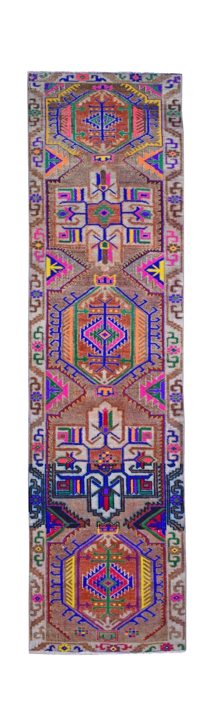 A vintage Kurdish Herki runner featuring vibrant tribal motifs on a brown wool base.