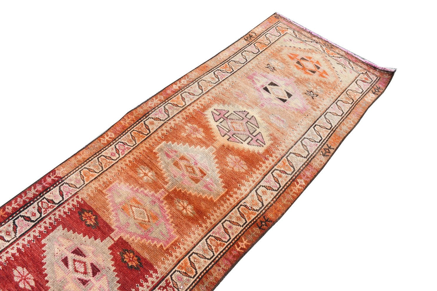 A vintage handmade Kurdish Herki runner featuring tribal motifs in orange and pink tones.