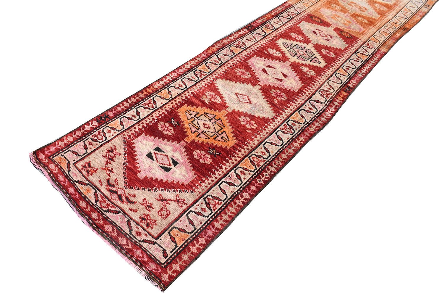 A vintage Kurdish Herki runner featuring tribal geometric motifs in red, pink, and orange tones.