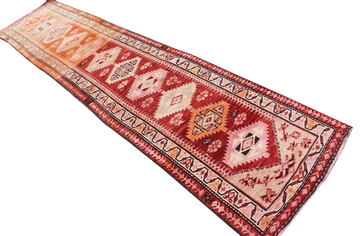 A vintage handmade Kurdish Herki runner featuring tribal diamond motifs in red and orange tones.