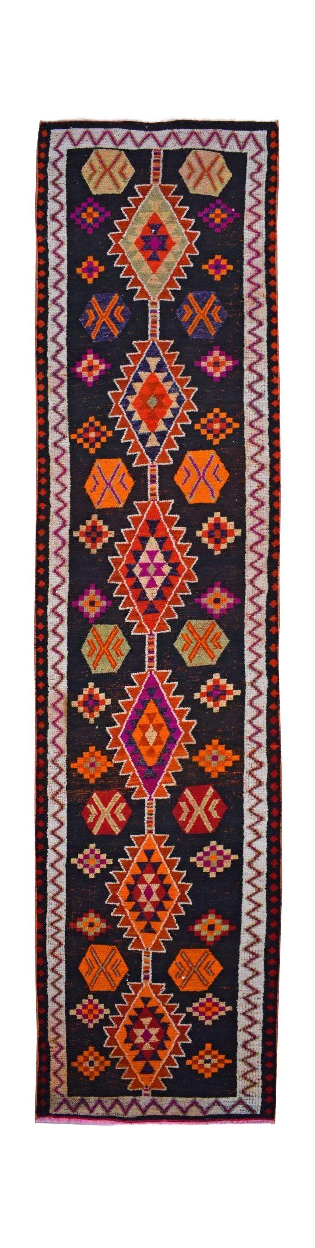 A vintage Kurdish Herki runner featuring a black field with colorful tribal geometric motifs.