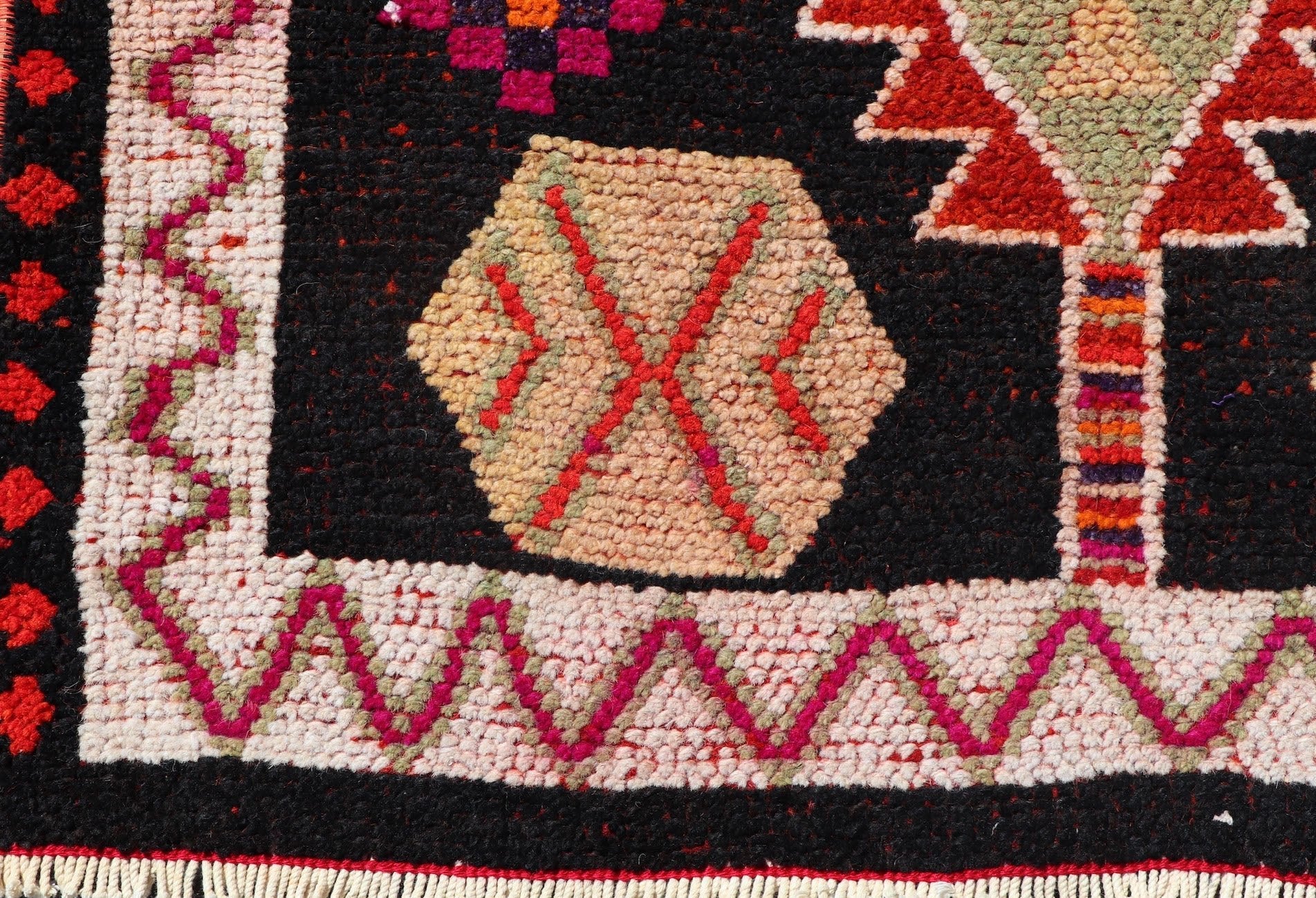 A vintage Kurdish Herki runner featuring tribal motifs in vibrant colors on a black wool background.