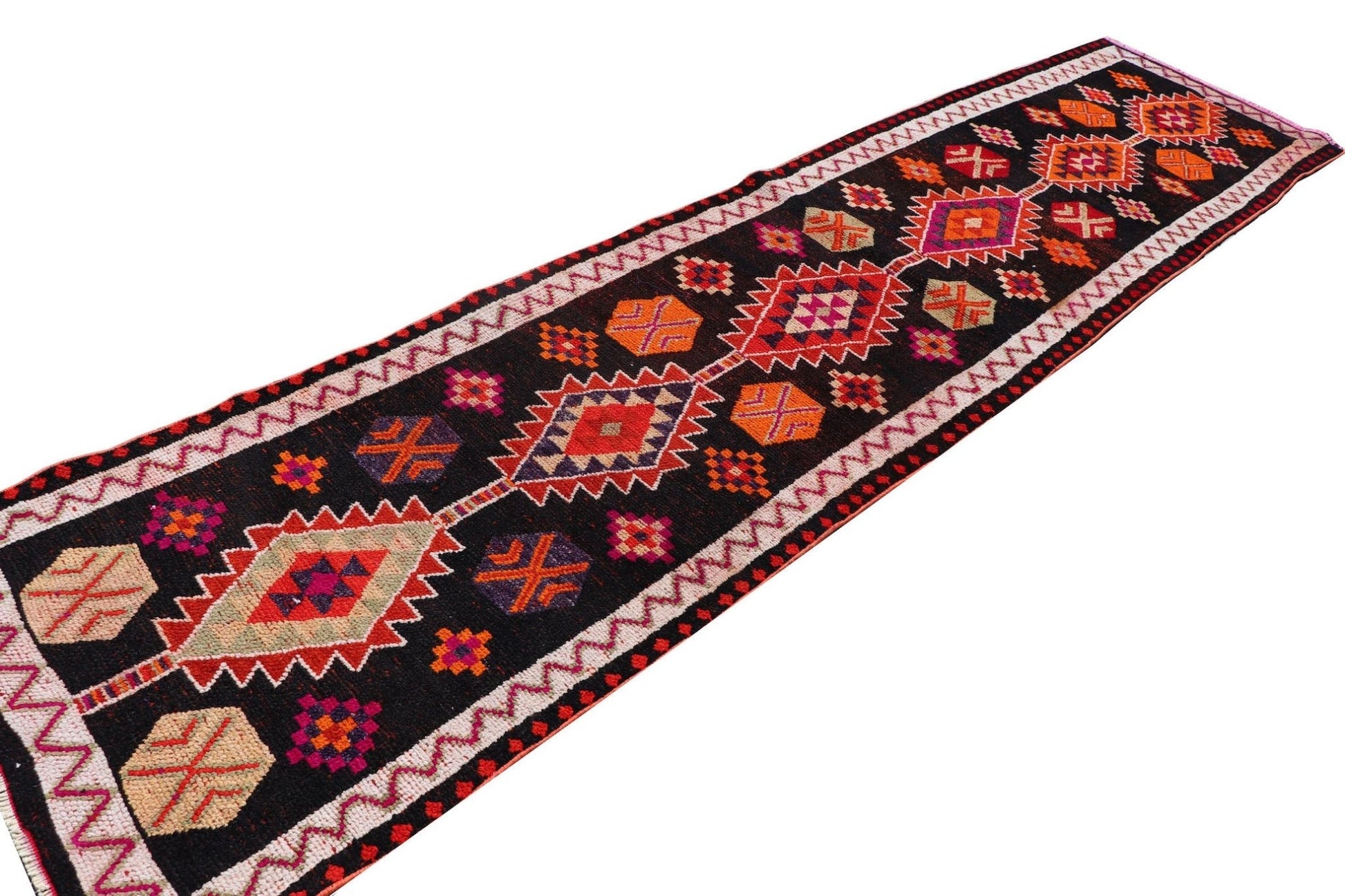 A vintage Kurdish Herki runner featuring a black wool base with vibrant tribal geometric patterns.