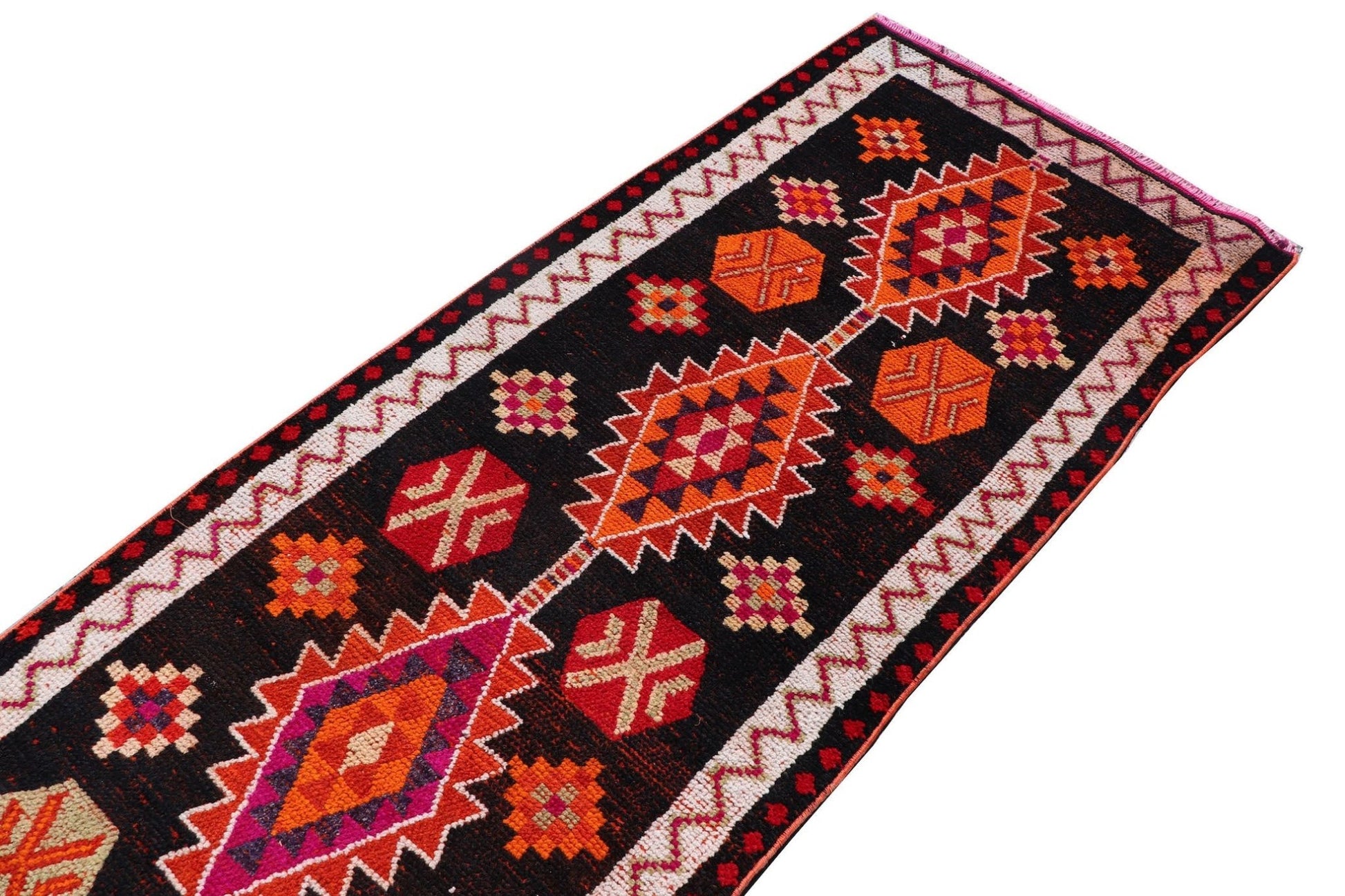 A vintage Kurdish Herki runner featuring tribal geometric motifs in vibrant colors on a black field.