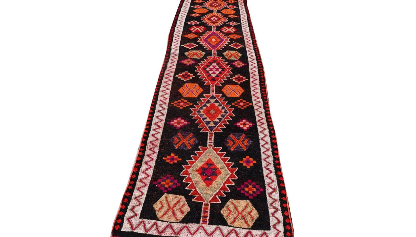 A vintage Kurdish Herki runner featuring tribal geometric motifs in vibrant colors on a black base.