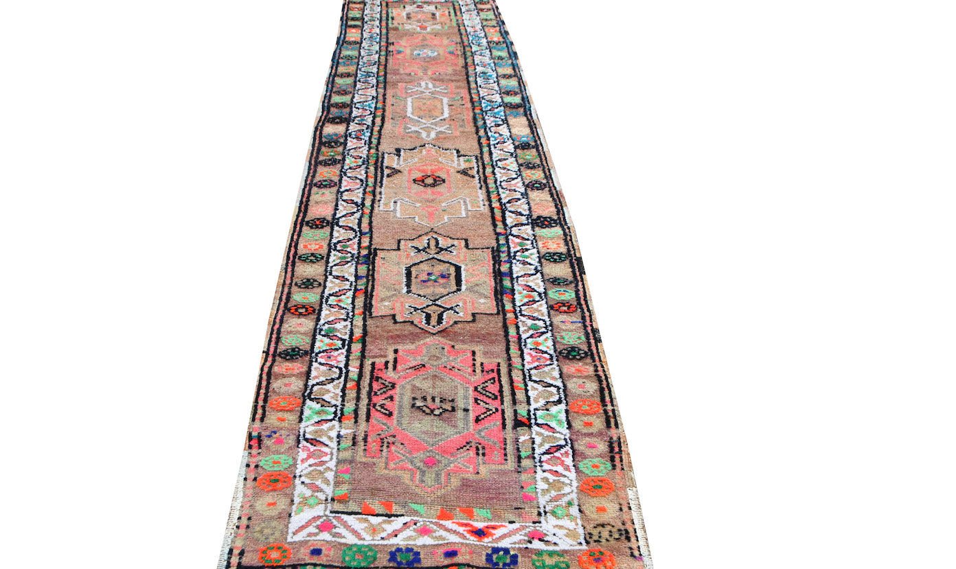 A vintage Kurdish Herki runner featuring tribal motifs in neon colors on a wool base.