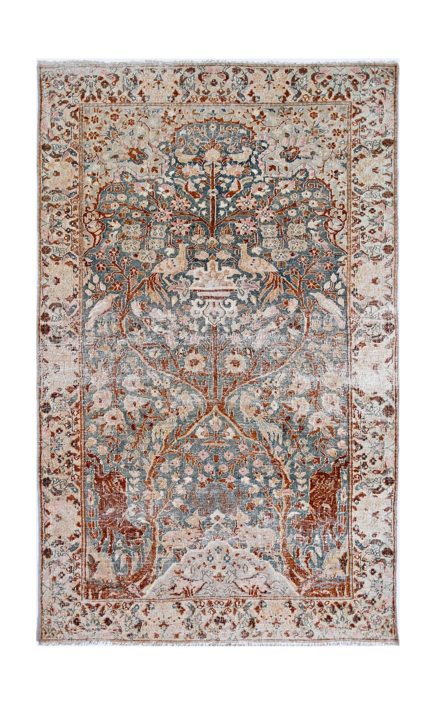 A vintage Persian Kerman rug featuring an intricate tree of life design in muted blue and rust tones.
