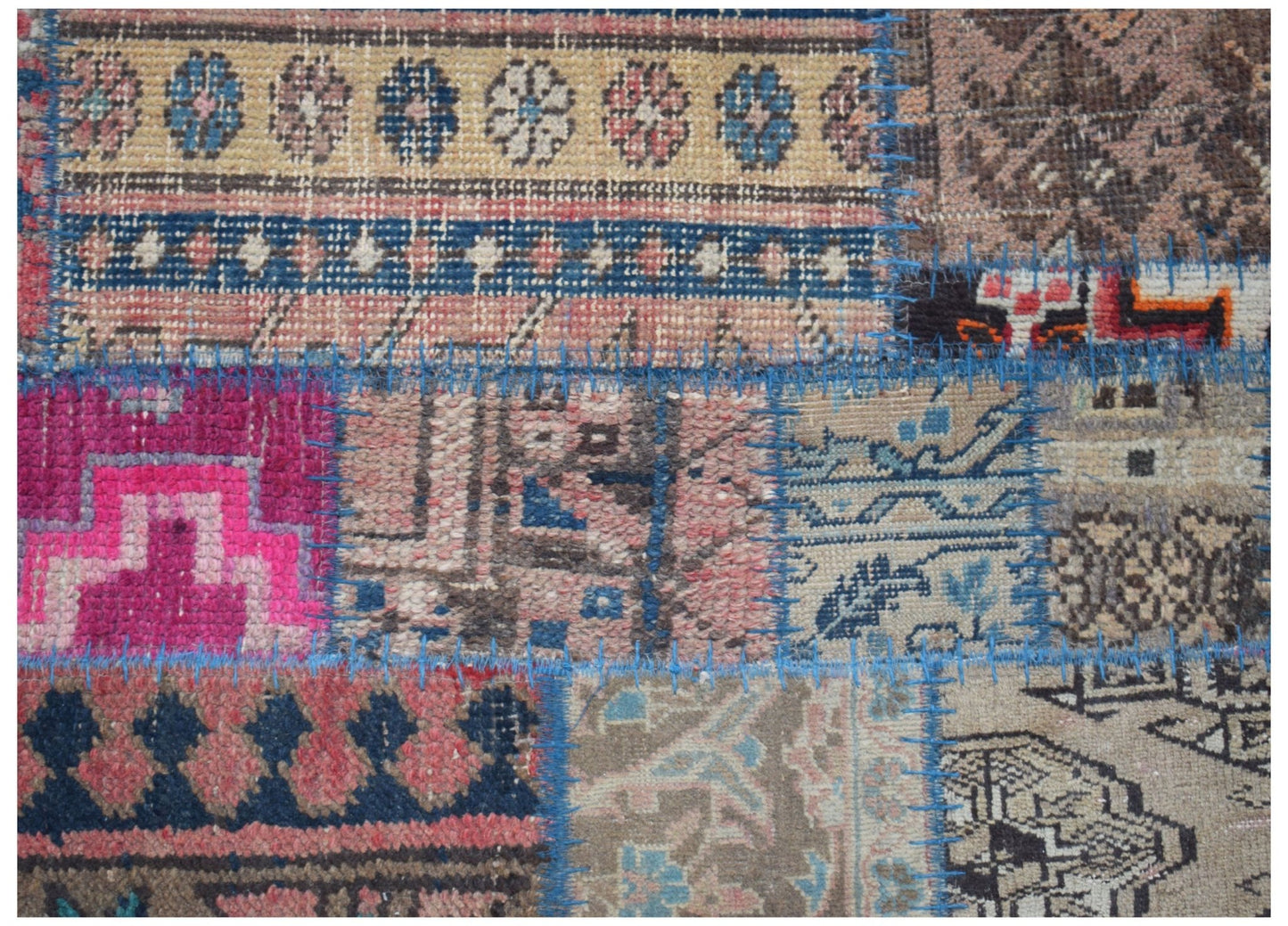 A handmade vintage patchwork runner featuring various wool rug fragments joined by blue stitching.