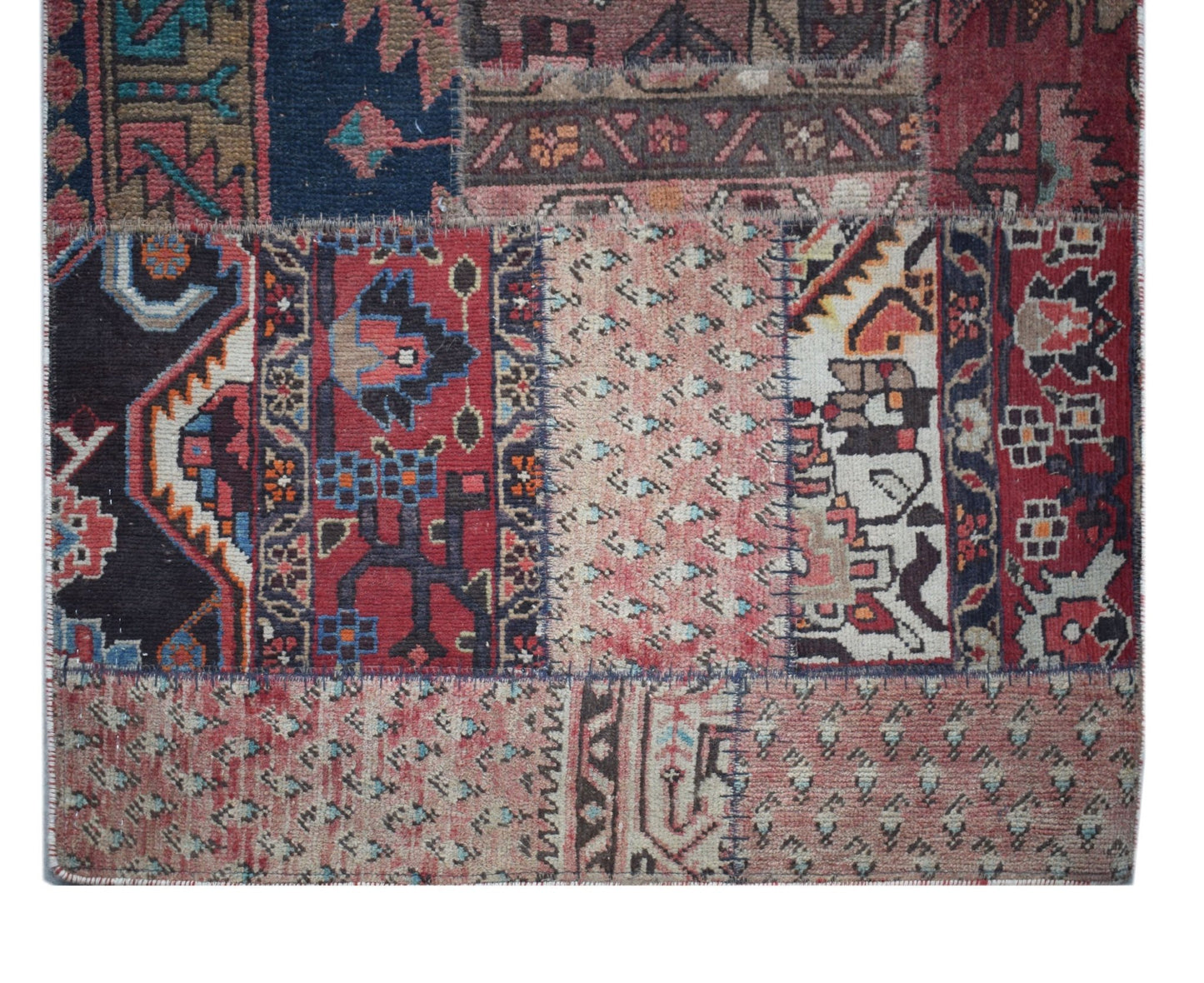 A handmade vintage patchwork runner featuring a variety of colorful wool rug fragments.