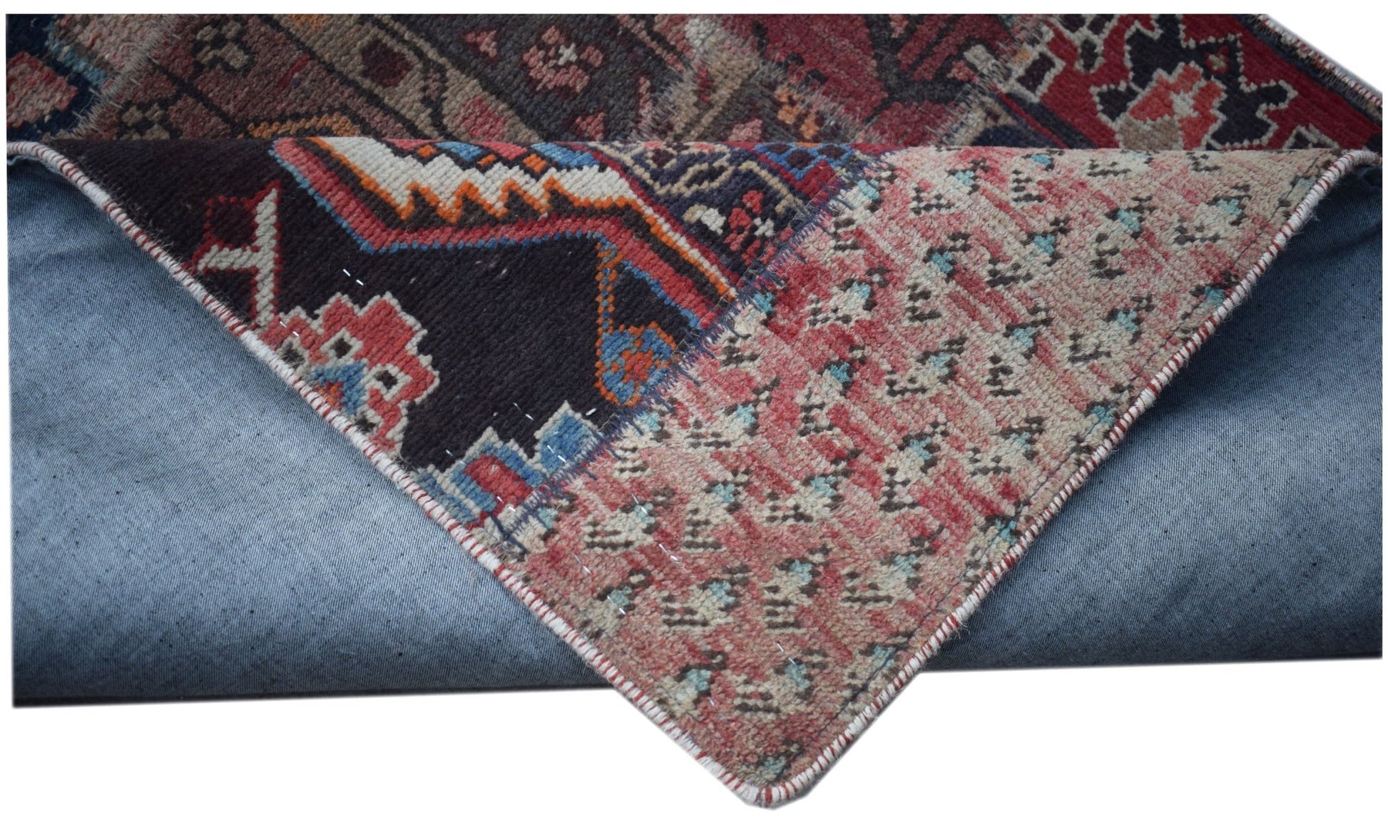 A vintage patchwork runner with a folded corner revealing its wool and cotton construction.