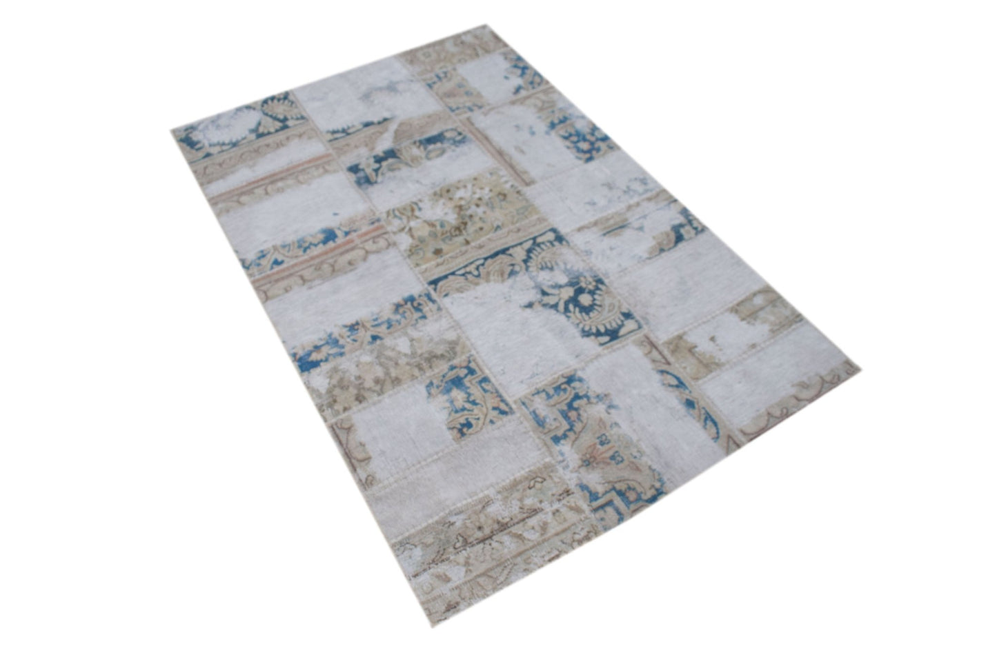 A rectangular handmade rug featuring a vintage patchwork design in shades of blue, beige, and cream.