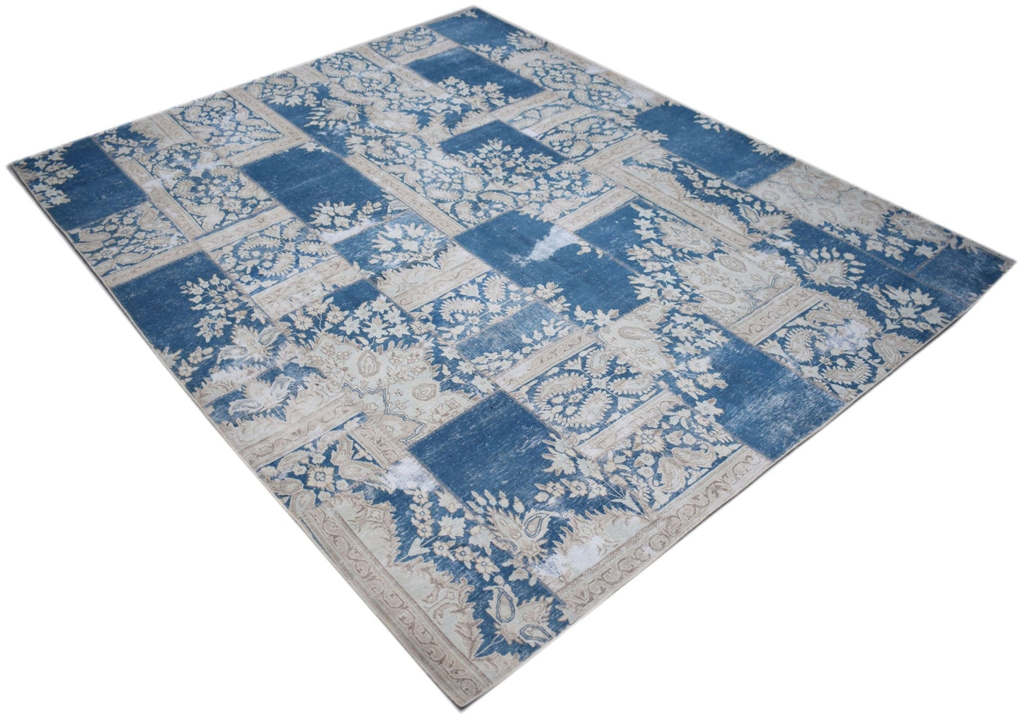 A rectangular vintage patchwork rug featuring a blue and cream floral pattern.