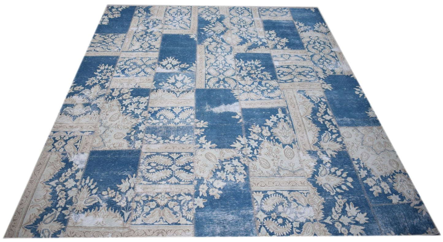 A rectangular handmade wool rug featuring a blue and cream vintage-style patchwork floral pattern.