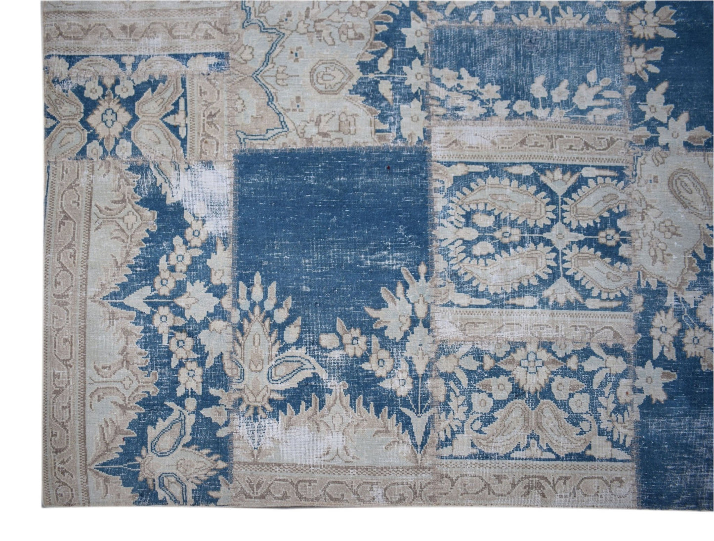 A handmade vintage patchwork rug featuring a blue and beige floral pattern.