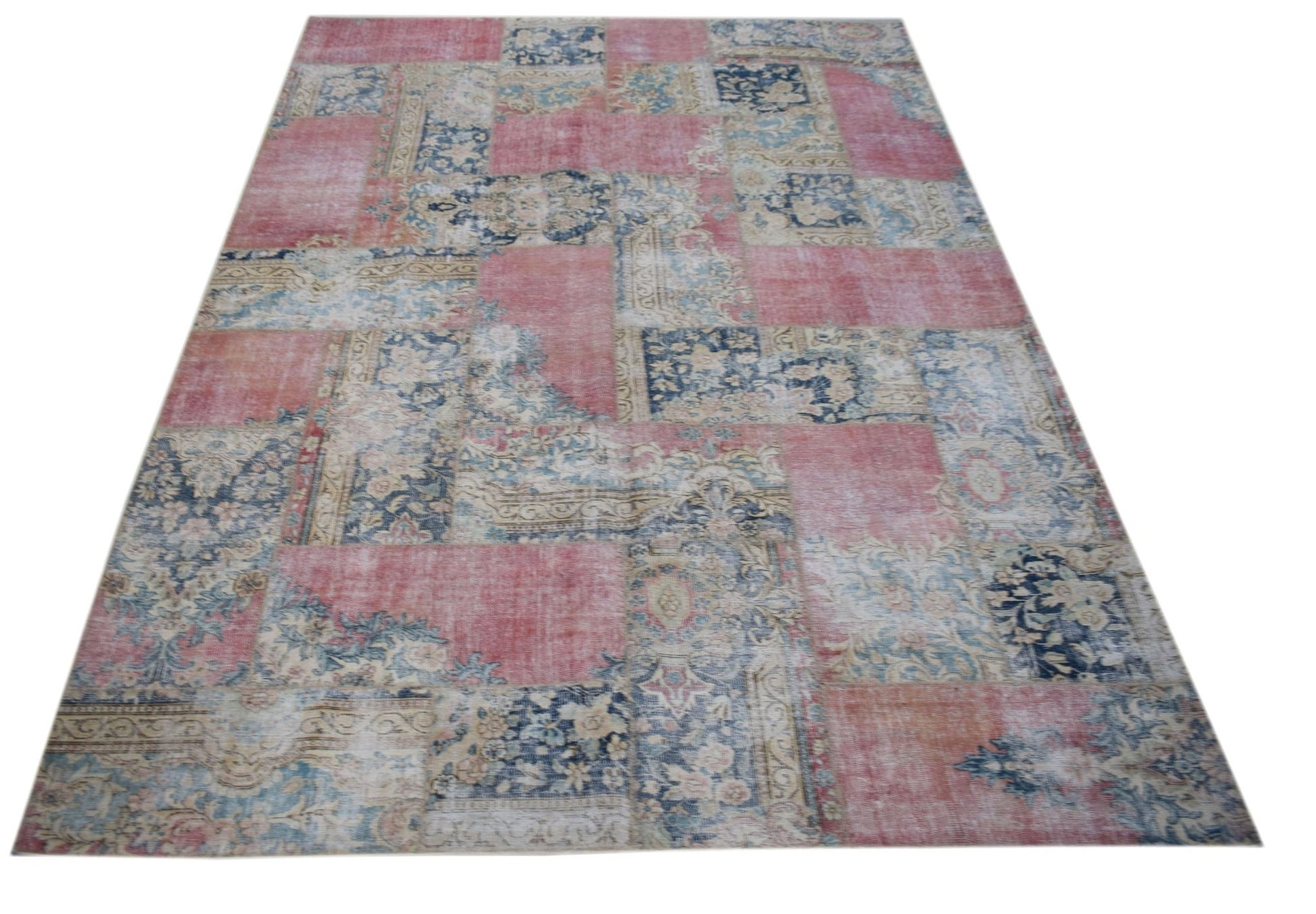 A rectangular vintage patchwork rug featuring a distressed pattern of pink and blue floral motifs.