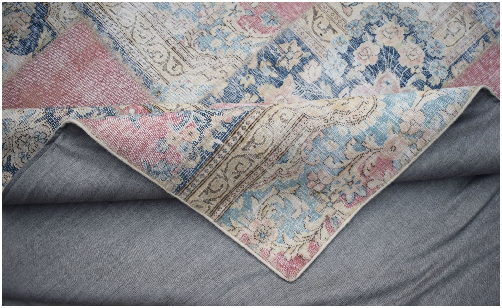 A handmade vintage patchwork rug featuring floral patterns in blue, pink, and cream tones.