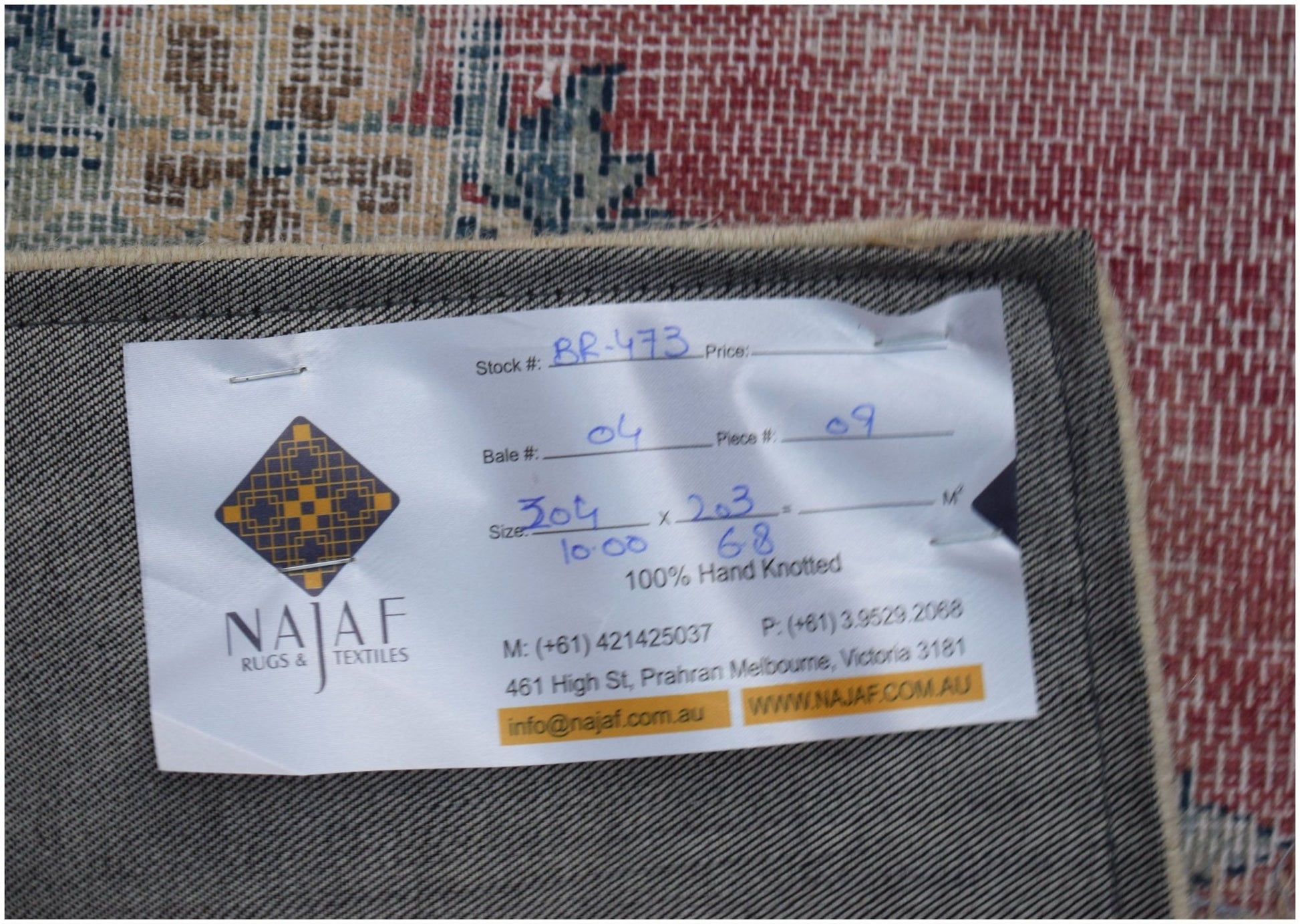 A vintage patchwork rug with a hand-knotted wool construction and a detailed label on the back.