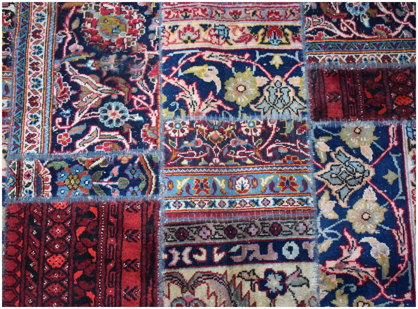 A handmade patchwork rug featuring a variety of vintage floral and geometric patterns in wool.