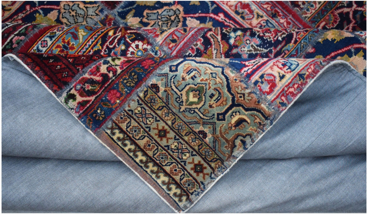 A vintage patchwork rug with intricate floral patterns in blue, red, and beige wool on cotton.