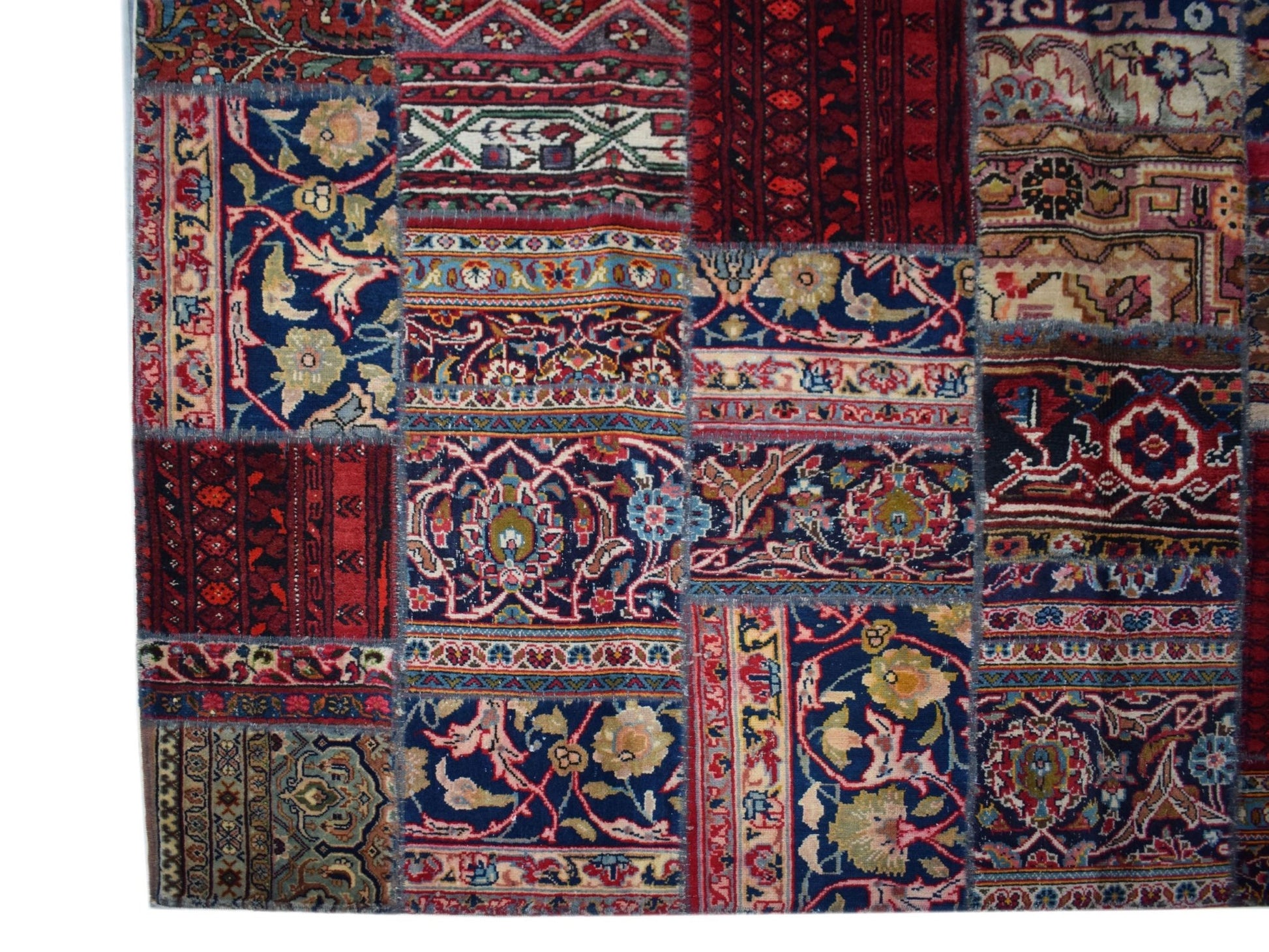 A handmade patchwork rug featuring a variety of vintage wool patterns in rich red and blue tones.